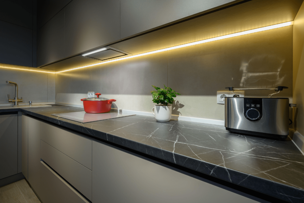 Küchenarbeitsplatte aus dunklem Stein mit eleganter Maserung in moderner Küche, beleuchtet durch warmes LED-Licht.